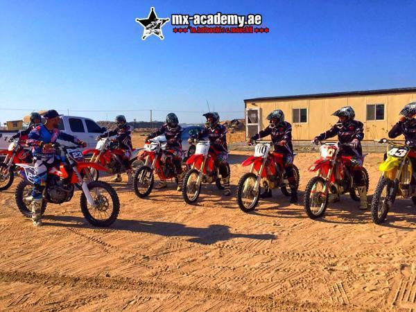 Dirt bike rental in Dubai: riders in full gear on red Honda and orange KTM bikes lined up on the sand